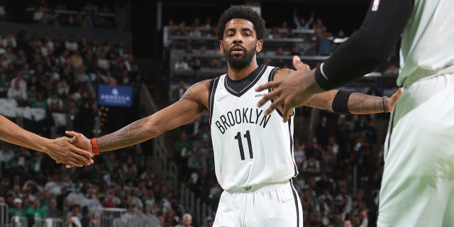 Kyrie Irving of the Brooklyn Nets high-fives teammates during the 2022 NBA playoff game against the Celtics on April 17, 2022, at the TD Garden in Boston.