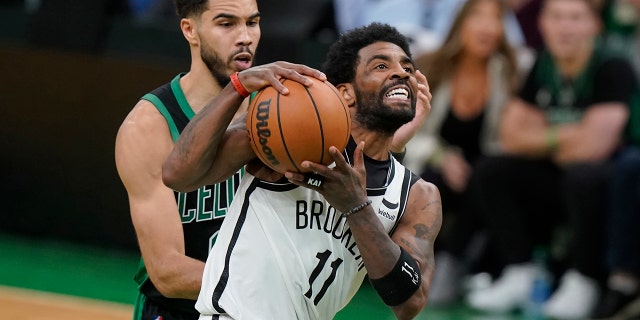 Brooklyn Nets guard Kyrie Irving (11) drives toward the basket as Boston Celtics forward Jayson Tatum (0) defends in the second half of Game 1 of an NBA basketball first-round Eastern Conference playoff series, Sunday, April 17, 2022, in Boston. The Celtics won 115-114.
