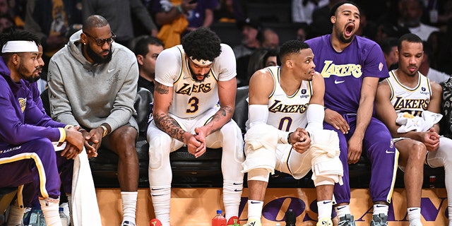 Lakers players including from left, LeBron James, Anthony Davis and Russell Westbrook sit with teammates on the bench late in the game against the Nuggets at Crypto.com Arena, Sunday April 3, 2022.