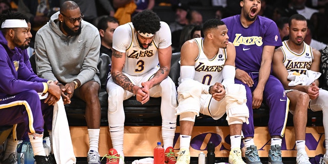 Lakers players including from left, LeBron James, Anthony Davis and Russell Westbrook sit with teammates on the bench late in the game against the Nuggets at Crypto.com Arena, Sunday April 3, 2022.