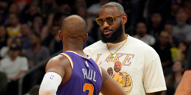 Los Angeles Lakers forward LeBron James talks with Phoenix Suns guard Chris Paul during the first half of an NBA basketball game Tuesday, April 5, 2022, in Phoenix.