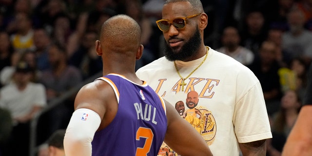 Los Angeles Lakers forward LeBron James talks with Phoenix Suns guard Chris Paul during the first half of an NBA basketball game Tuesday, April 5, 2022, in Phoenix.