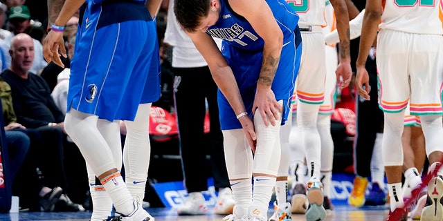 Dallas Mavericks' Luka Doncic (77) reaches for his lower leg after suffering an unknown lower leg injury in the second half of an NBA basketball game against the San Antonio Spurs, Domenica, aprile 10, 2022, a Dallas.