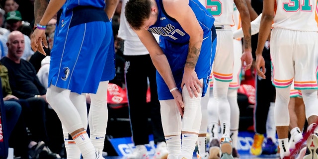 Dallas Mavericks' Luka Doncic (77) reaches for his lower leg after suffering an unknown lower leg injury in the second half of an NBA basketball game against the San Antonio Spurs, Domenica, aprile 10, 2022, a Dallas.