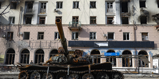 A destroyed tank and a damaged apartment building from heavy fighting are seen in an area controlled by Russian-backed separatist forces in Mariupol, Ukraine, on Tuesday, April 26.