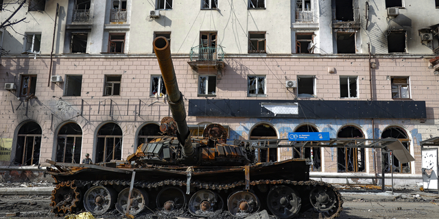 A destroyed tank and a damaged apartment building are seen in an area controlled by Russian-backed separatist forces in Mariupol, Ukraine, on Tuesday, April 26.