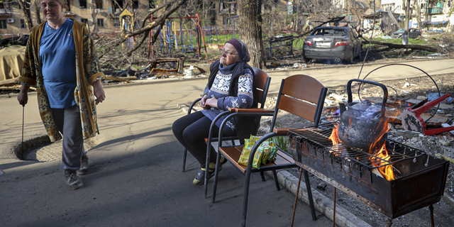 Miestne ženy sa v utorok 26. apríla zhromažďujú pri vchode do zničeného bytového domu v Mariupole na Ukrajine.