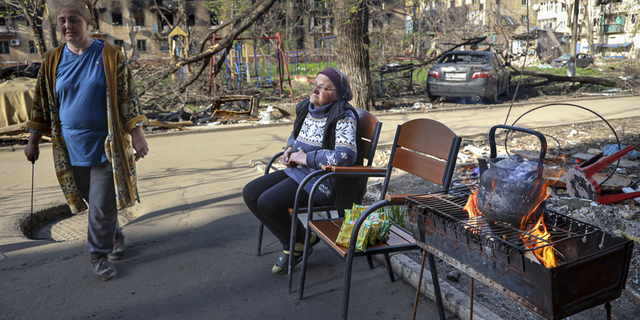 Local women gather at an entrance of a damaged apartment building in Mariupol, Ukraine, on Tuesday, April 26.