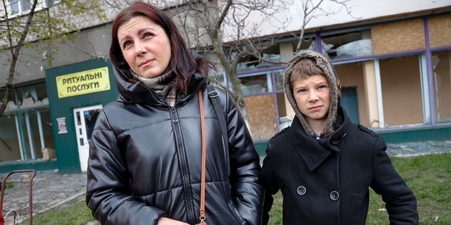 Local civilians, a mother and her son, speak to journalists in an area controlled by Russian-backed separatist forces in Mariupol, Ukraine, Friday, April 22, 2022. (AP Photo/Alexei Alexandrov)