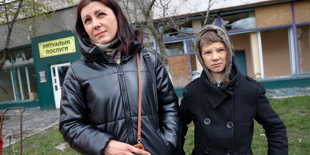Local civilians, a mother and her son, speak to journalists in an area controlled by Russian-backed separatist forces in Mariupol, Ukraine, Friday, April 22, 2022. (AP Photo/Alexei Alexandrov)