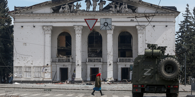 A woman walks next to an armored vehicle belonging to pro-Russian troops in Mariupol, Ukraine, on Sunday.