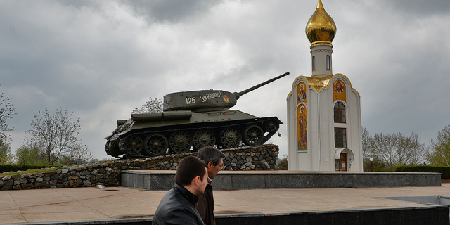 Mọi người đi ngang qua một chiếc xe tăng thời Liên Xô, hiện là tượng đài kỷ niệm chiến thắng của Hồng quân chống lại phát xít Đức, ở Tiraspol, thành phố chính của Transnistria, Moldova, vào tháng 4 năm 2014.