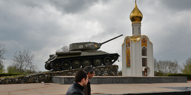 Les gens passent à côté d'un char de l'ère soviétique, devenu un monument célébrant la victoire de l'Armée rouge contre l'Allemagne fasciste, à Tiraspol, la principale ville de la région séparatiste trans-Dniestr de Moldavie, en avril 2014.