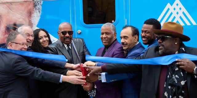Robert F. Smith (center) joins Steve Harvey, Chris Tucker and Cedric the Entertainer and members of the Mount Sinai Health System to cut the ribbon of the mobile cancer unit. 