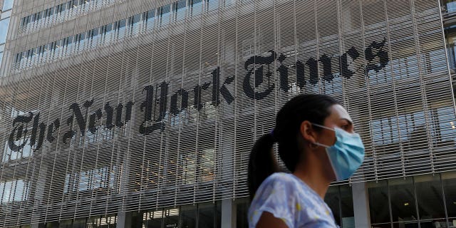 A woman wearing a protective face mask walks past the New York Times building in Manhattan, New York, US, on August 3, 2020.  REUTERS/Shannon Stapleton 