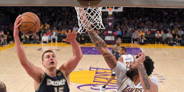Denver Nuggets center Nikola Jokic, left, shoots as Los Angeles Lakers forward Anthony Davis defends during the first half of an NBA basketball game Sunday, April 3, 2022, in Los Angeles. 