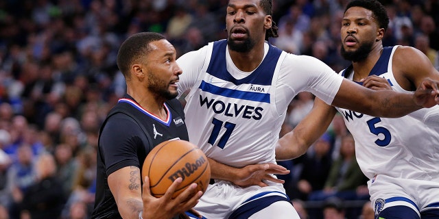 Los Angeles Clippers forward Norman Powell (24) drives on Minnesota Timberwolves' Naz Reid (11) and Malik Beasley (5) during the first quarter during an NBA basketball game Tuesday, April 12, 2022, in Minneapolis.