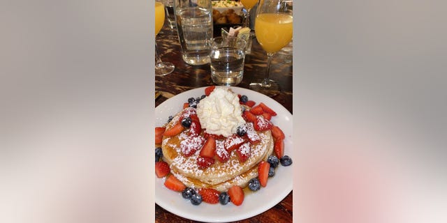 Strawberry and blueberry pancakes topped with whipped cream are served at Pardon My French in New York City, Nov. 22, 2020. (Nicole Rose)