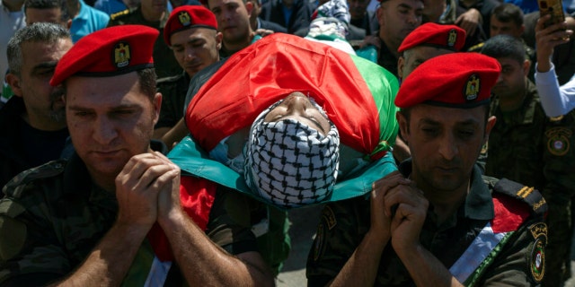 Palestinian security officers carry the body of Muhammad Assaf, 34 during his funeral in the West Bank village of Kufr Laqef, near Qalqiliya, Wednesday, April 13, 2022. Israeli forces shot and killed a Palestinian man during clashes on Wednesday, the Palestinian Health Ministry said, as Israeli troops continued a days-long operation in the occupied West Bank in response to a spate of deadly attacks.