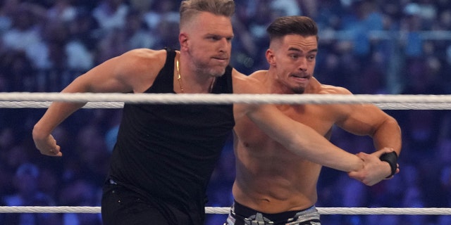 Pat McAfee (black pants) and Austin Theory (black trunks) wrestle during WrestleMania at AT&T Stadium in Arlington, Texas, on Apr 3, 2022.