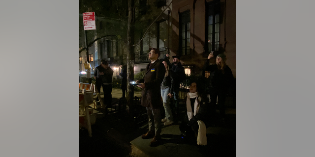 People watch as a Ukrainian activist group defiantly bathed the Manhattan townhouse of Russia's U.N. ambassador in the blue and yellow colors of the Ukrainian flag.