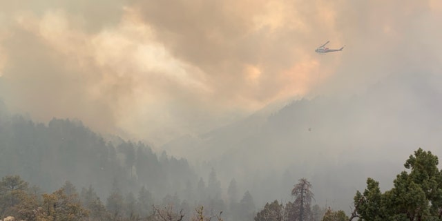 A helicopter flies over smoky skies from Arizona's Crooks Fire