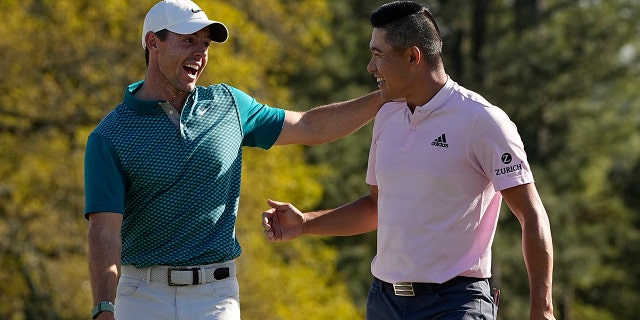 Rory McIlroy, of Northern Ireland, talks to Collin Morikawa after they both holed out from the bunker for a birdie during the final round at the Masters golf tournament on Sunday, April 10, 2022, in Augusta, Ga.