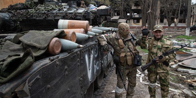 Russian soldiers pose by a T-80 tank in a position close to the Azovstal frontline in the besieged port city of Mariupol. 