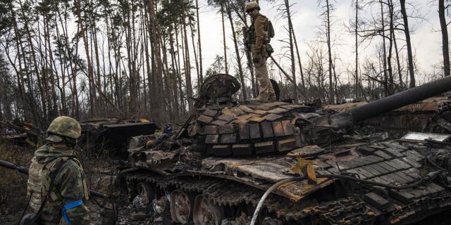 A Ukrainian soldier stands one top of a destroyed Russian tank on the outskirts of Kyiv, Ukraine, Thursday, March 31, 2022. (AP Photo/Rodrigo Abd)