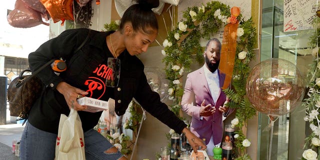 Kay Harris, the sister of shooting victim Sergio Harris, places a decoration by a photo of her slain brother at a memorial in Sacramento, Calif., Thursday, April 7, 2022. Six people were killed and many others were injured in the shooting April, 3, 2022.