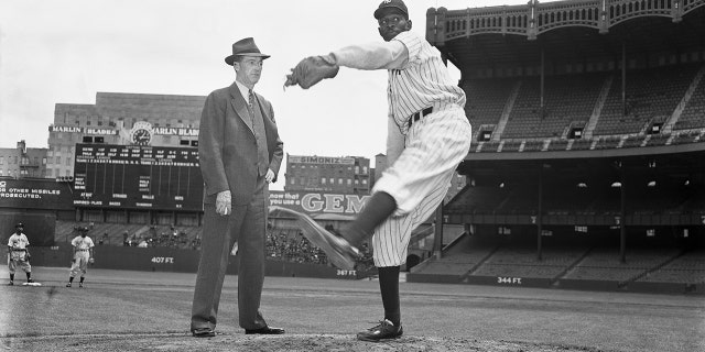 Baseball Hall of Famer Grover Cleveland Alexander stands on the pitcher's mound at Yankee Stadium and watches pitcher Satchel Paige at work. Paige was a member of the New York Black Yankees.