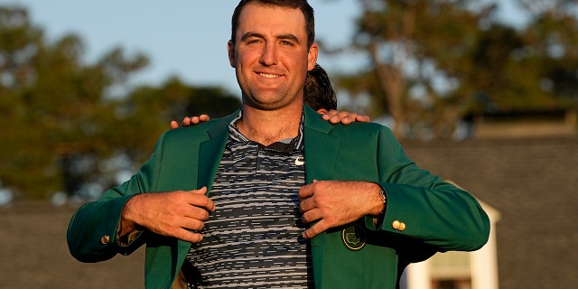 Hideki Matsuyama, of Japan, helps Scottie Scheffler put on the green jacket after winning the 86th Masters golf tournament on Sunday, April 10, 2022, in Augusta, Ga.