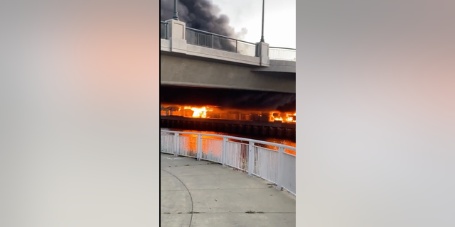 A large fire burns under a bridge in Oakland, California on April 28, 2022.