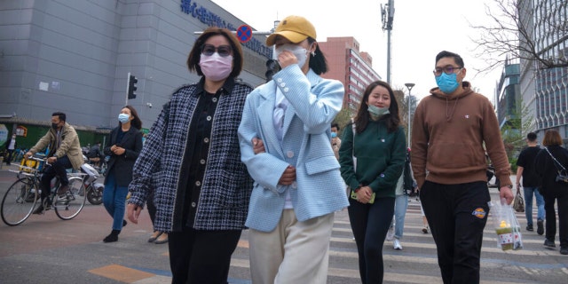 People wearing face masks cross an intersection in Beijing on Wednesday, April 13, 2022.
