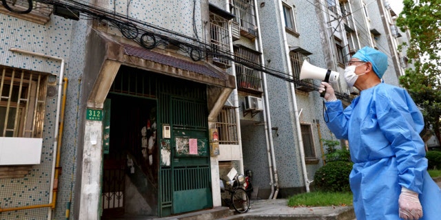 In this photo released by China’s Xinhua News Agency, a volunteer uses a megaphone to talk to residents at an apartment building in Shanghai, China, Tuesday, April 12, 2022. Shanghai has released more than 6,000 more people from medical observation amid a COVID-19 outbreak, the government said Wednesday, but moves to further ease the lockdown on China’s largest city appeared to have stalled. 