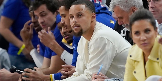 Golden State Warriors guard Stephen Curry, middle, watches during the first half of the team's NBA basketball game against the Los Angeles Lakers in San Francisco, Thursday, April 7, 2022.