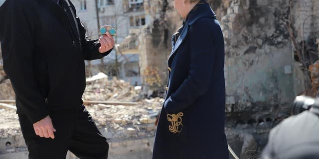 Steve Daines picks up a child's wooden toy found near the mass graves in Makariv.