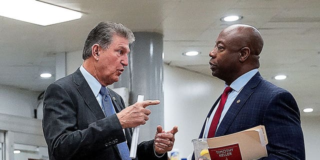 Le sénateur américain Joe Manchin (D-WV) s'entretient avec le sénateur Tim Scott (R-SC) dans le métro du Sénat au Capitole américain à Washington, États-Unis, le 15 décembre 2021.