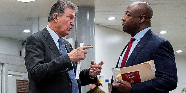 Le sénateur américain Joe Manchin (D-WV) s'entretient avec le sénateur Tim Scott (R-SC) dans le métro du Sénat au Capitole américain à Washington, États-Unis, le 15 décembre 2021.