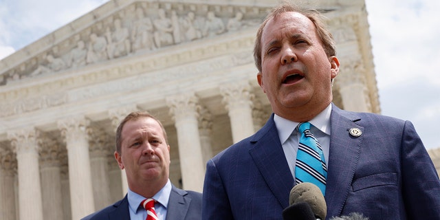 Texas Attorney General Ken Paxton, right, and Missouri Attorney General Eric Schmitt talk to reporters after the U.S. Supreme Court heard arguments in their case about Title 42.