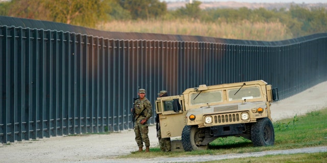 National Guardsmen stands watch over a fence near the International bridge where thousands of Haitian migrants have created a makeshift camp, on Sept. 18, 2021, in Del Rio, Texas. 