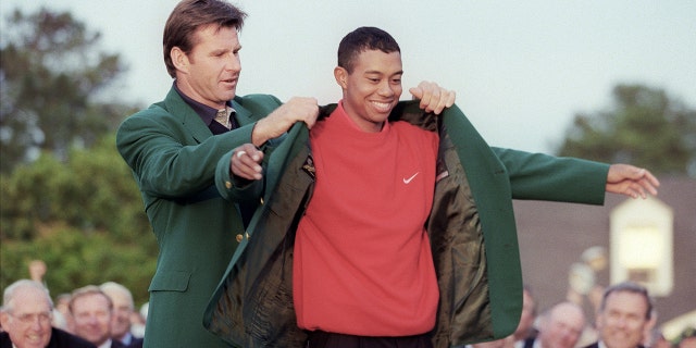 Tiger Woods receives the Masters green jacket from 1996 Masters champion Nick Faldo after Woods won the 1997 Masters tournament at Augusta National Golf Club in Georgia.