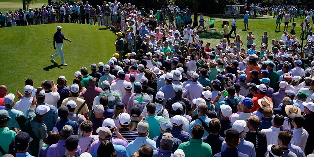 Spectators watch as Tiger Woods walks off the first green during a practice round for the Masters golf tournament on Monday, April 4, 2022, in Augusta, Georgia.