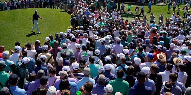 Spectators watch as Tiger Woods walks off the first green during a practice round for the Masters golf tournament on Monday, April 4, 2022, in Augusta, Georgia.