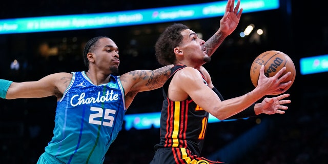Atlanta Hawks guard Trae Young, right, drives to the basket past Charlotte Hornets forward P.J. Washington during the first half, April 13, 2022, in Atlanta.