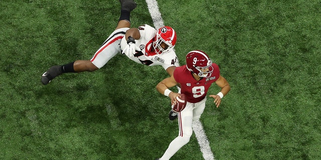 Bryce Young #9 of the Alabama Crimson Tide scrambles from Travon Walker #44 of the Georgia Bulldogs during the first quarter in the 2022 CFP National Championship Game at Lucas Oil Stadium on January 10, 2022, in Indianapolis, Indiana.