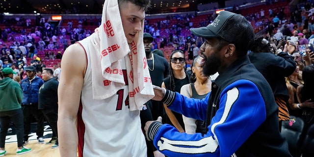 Miami Heat guard Tyler Herro, 剩下, talks with former boxer Floyd Mayweather Jr. after an NBA basketball game between the Heat and Charlotte Hornets, 星期二, 四月 5, 2022, 在迈阿密. The Heat won 144-115.