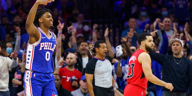 Philadelphia 76ers' Tyrese Maxey, links, reacts to his three-pointer as Toronto Raptors' Fred VanVleet, reg, looks on during the first half of Game 1 of an NBA basketball first-round playoff series, Saterdag, April 16, 2022, in Philadelphia.
