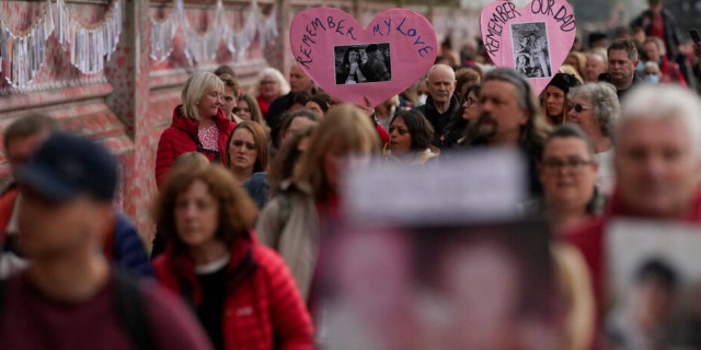 FILE — no COVID mirušo ģimenes locekļi otrdien, 2022. gada 29. martā, iet garām Nacionālajam Covid memoriālam Londonā. 