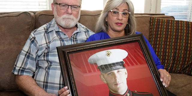 Joey and Paula Reed pose for a photo with a portrait of their son Marine veteran and Russian prisoner Trevor Reed at their home in Fort Worth, Texas, on Feb. 15, 2022.